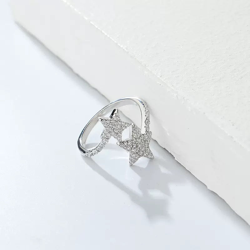 Silver ring with two pavé star designs on a minimalist white background