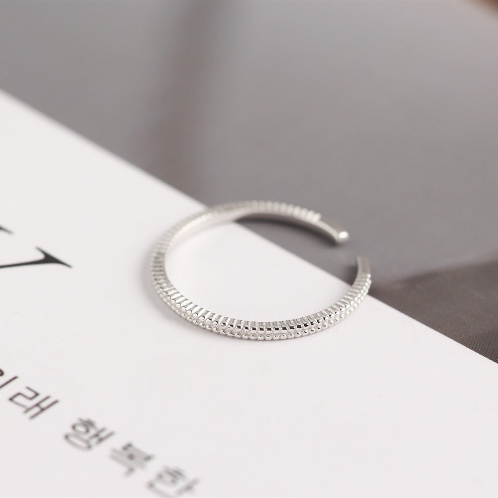 Minimalist silver textured ear cuff on a white and grey background