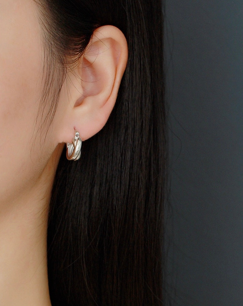 Minimalist silver hoop earring on ear, modern precious metal jewelry, close-up