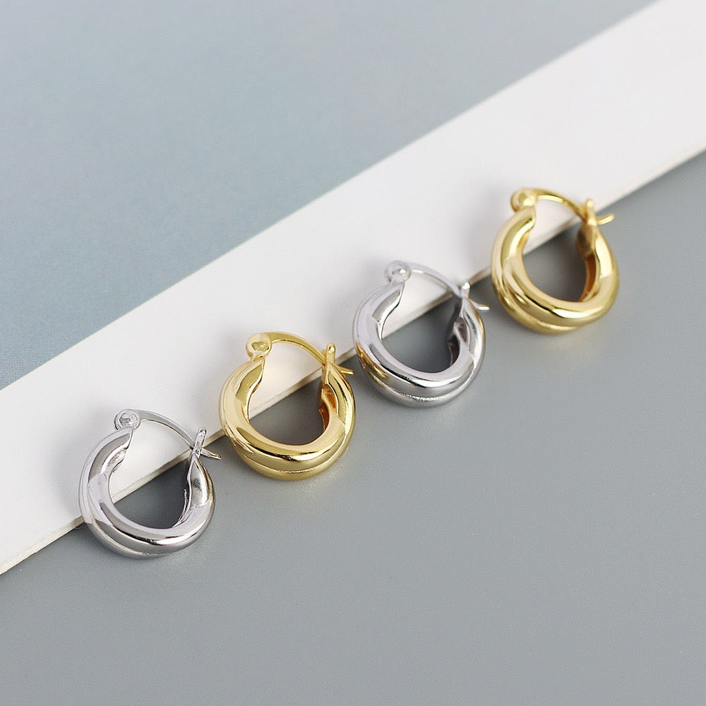Gold and silver minimalist chunky hoop earrings on a modern grey background