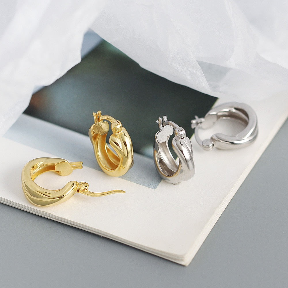 Gold and silver chunky minimalist hoop earrings on a book with soft light background