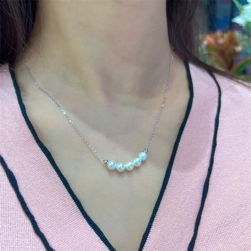 Silver necklace with pearls worn by a person.