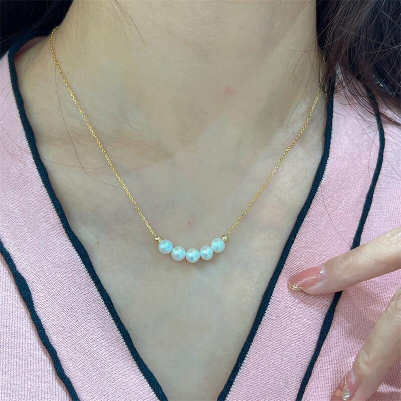 Gold necklace with pearls worn by a person.