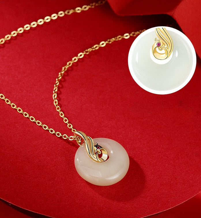Close up of Hetian jade Phoenix necklace showing carved jade pendant, ruby eye detail and gold plated finish