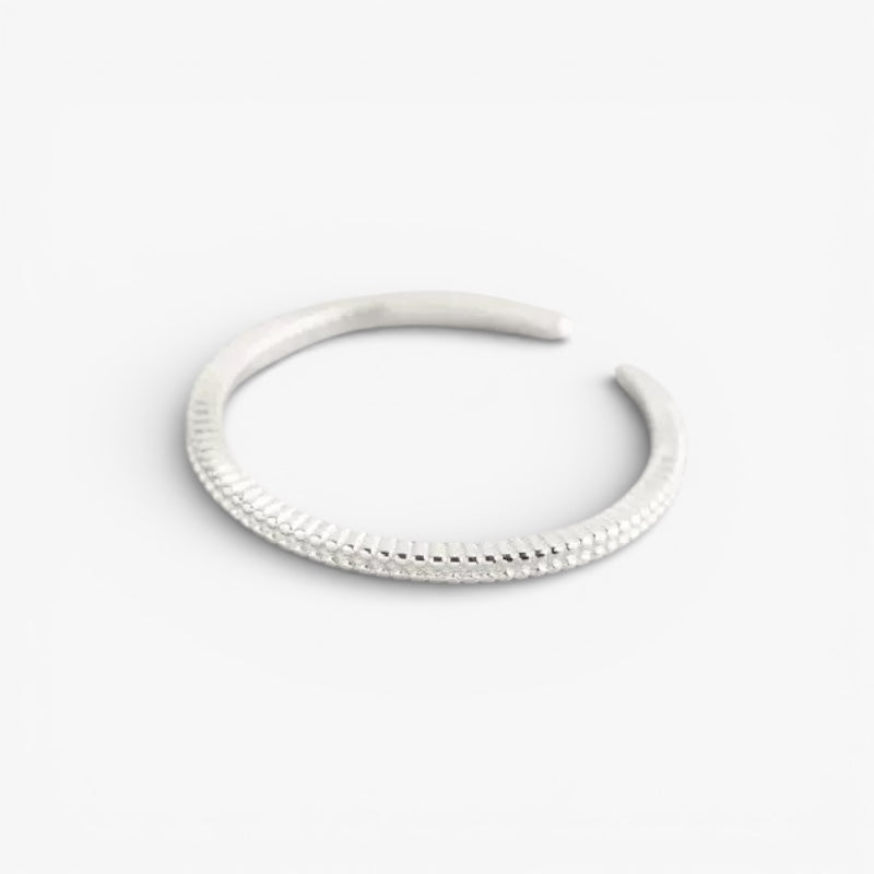 Minimalist silver textured open cuff bracelet on white background