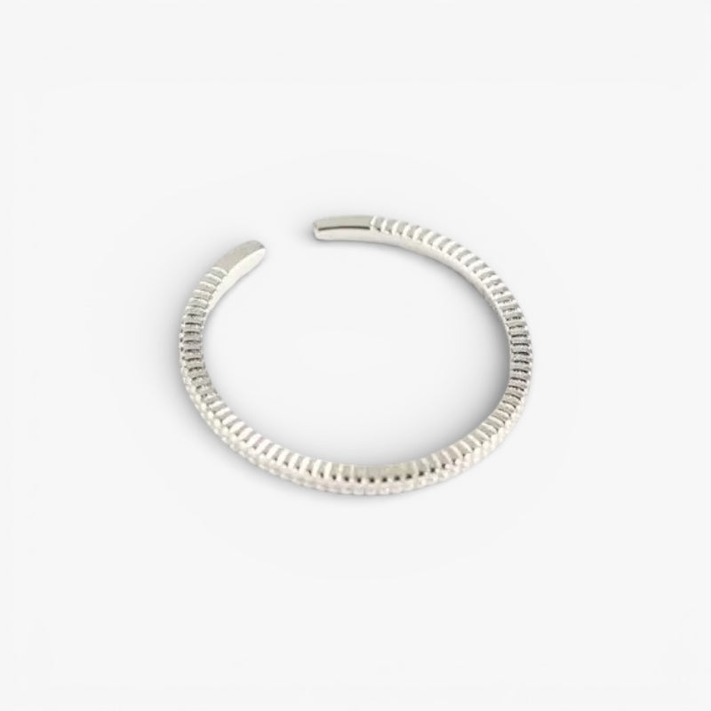 Textured minimalist silver open ring on white background, modern jewelry design