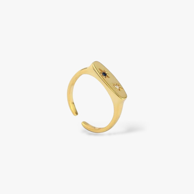 Minimalist gold open ring with starburst detailing and two gemstone inlays on white background