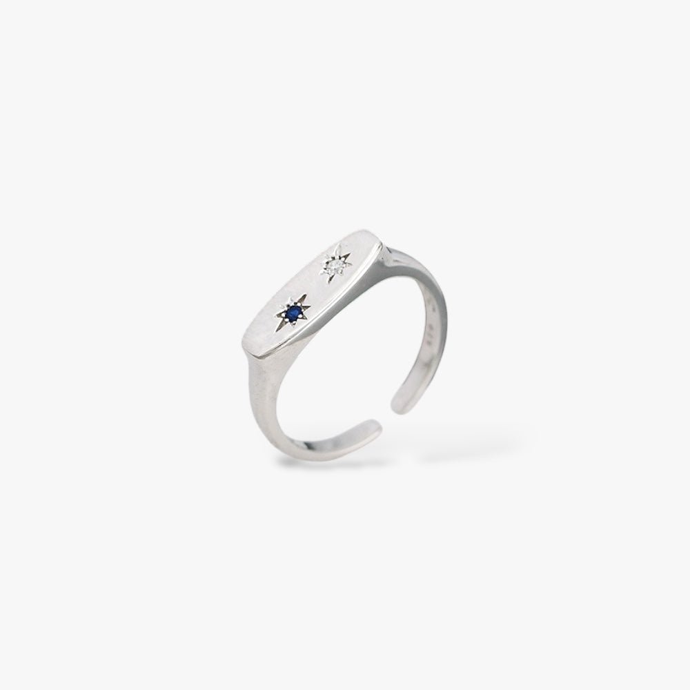Minimalist silver open ring with blue and clear gemstone star accents on white background