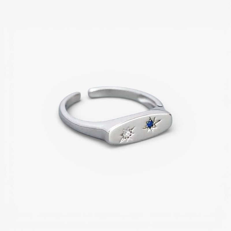 Minimalist silver open ring with star-set clear and blue gemstones on white background