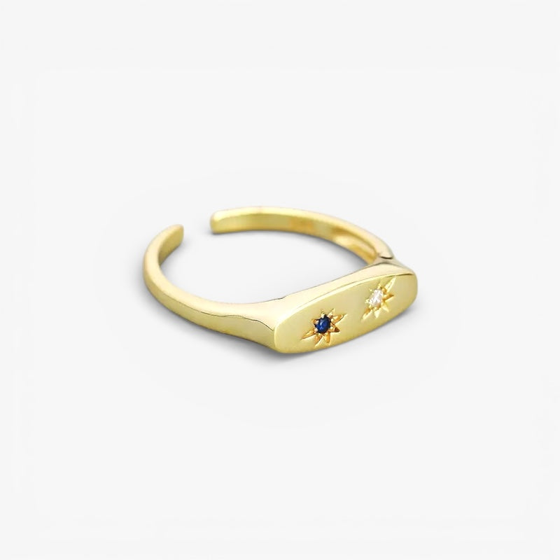 Minimalist gold open ring with blue and white gemstone star accents on a white background