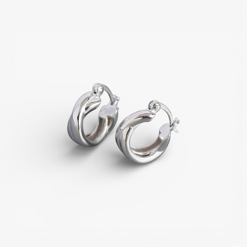 Chunky silver twisted hoop earrings on white background, minimalist modern style