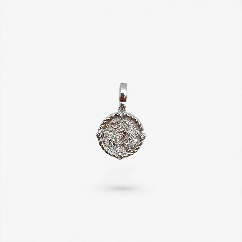 Textured silver round pendant with rope edge and small clear stones on white background
