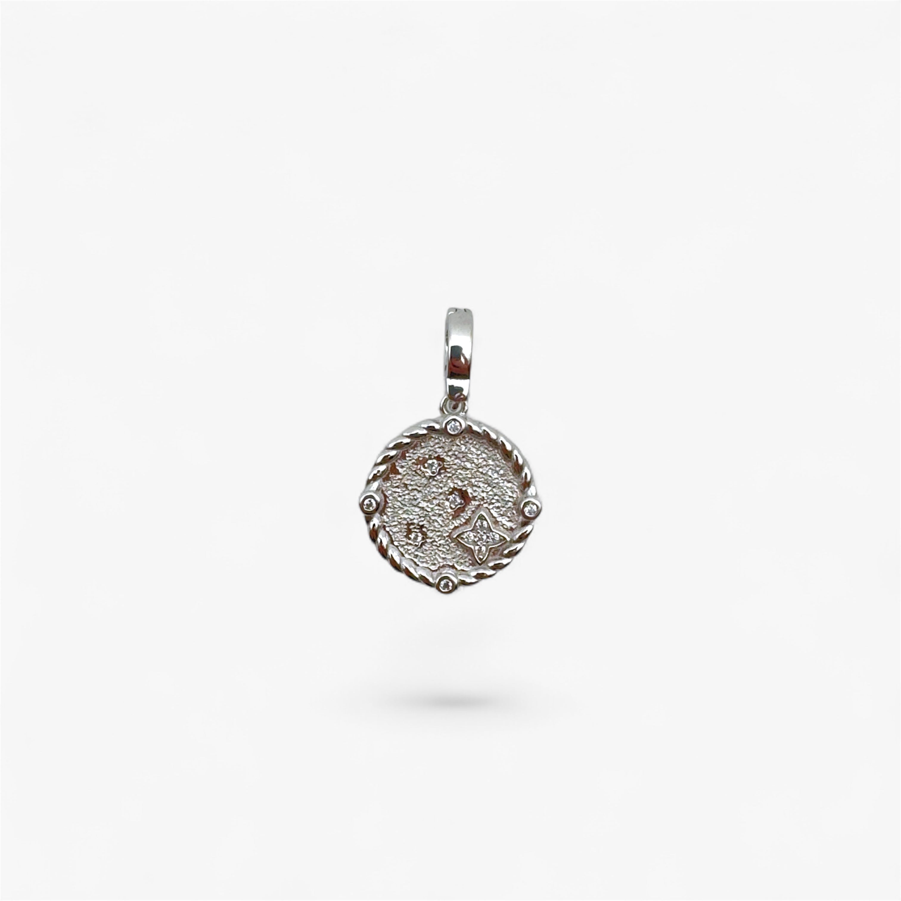 Textured silver round pendant with rope edge and small clear stones on white background