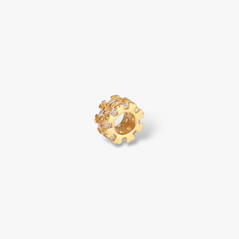 Gold gear-shaped charm bead with clear gemstones on white background