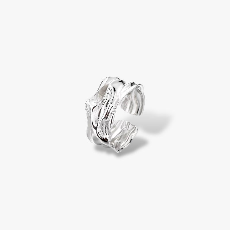 Modern minimalist silver ear cuff with textured, wavy design on white background