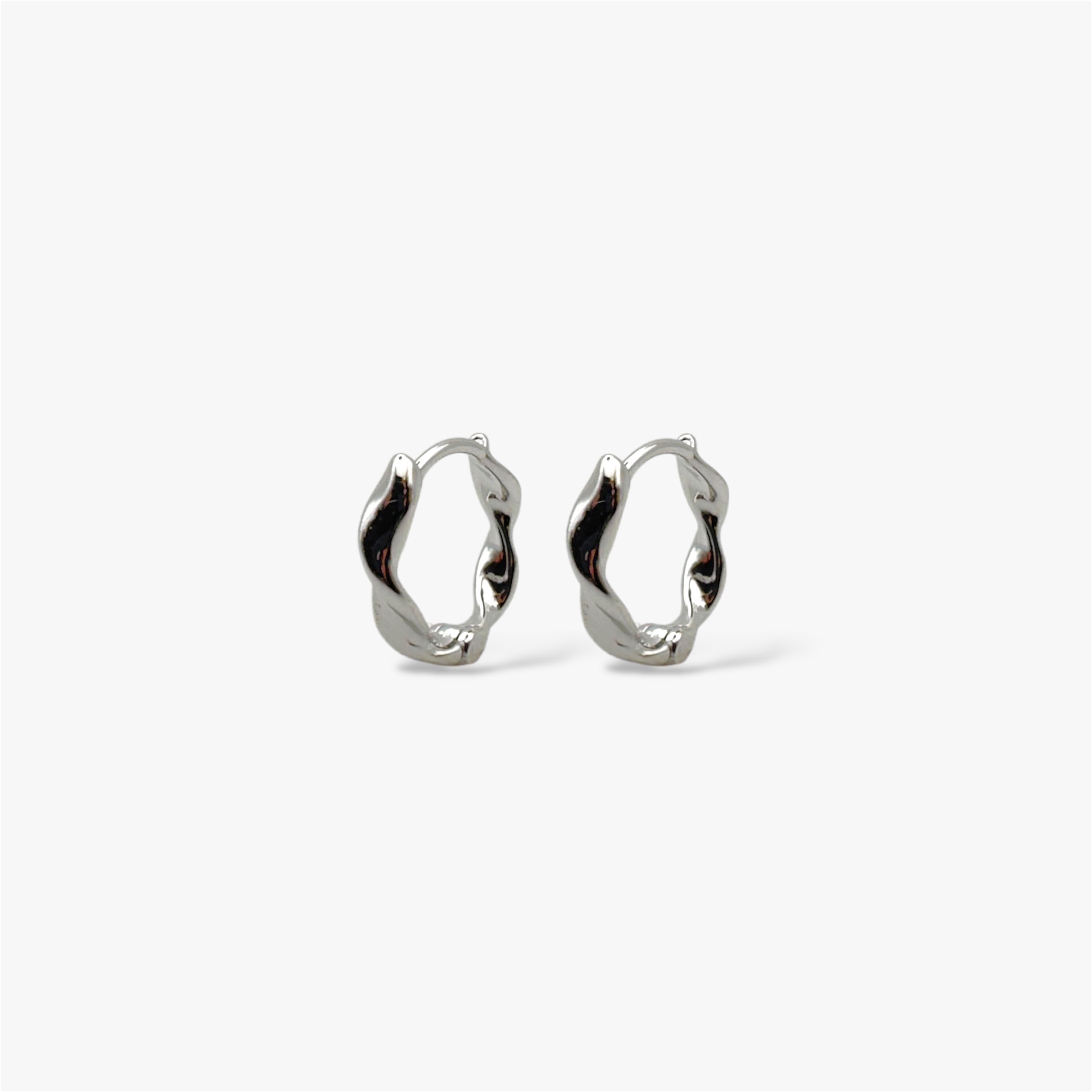 Organically-shaped silver huggie hoop earrings.