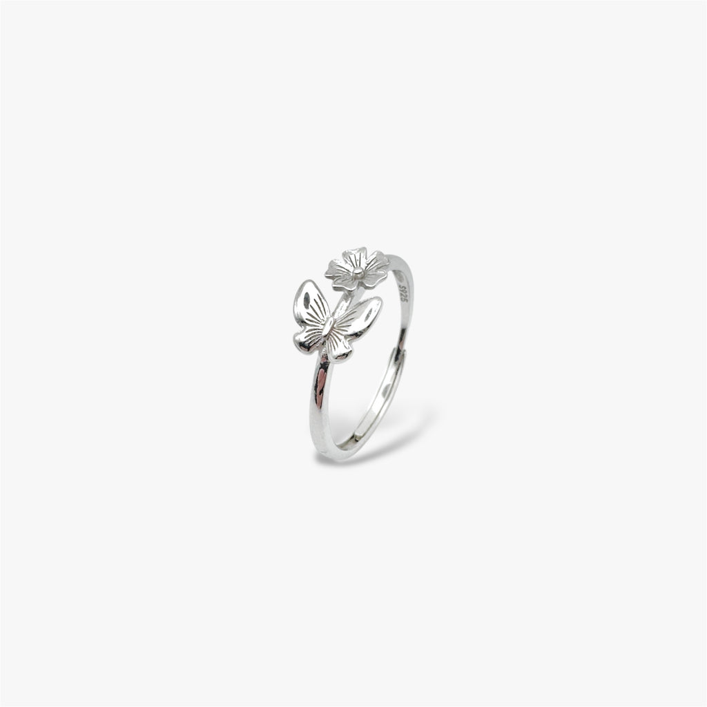Angled view of silver ring with a floral design and a butterfly design.