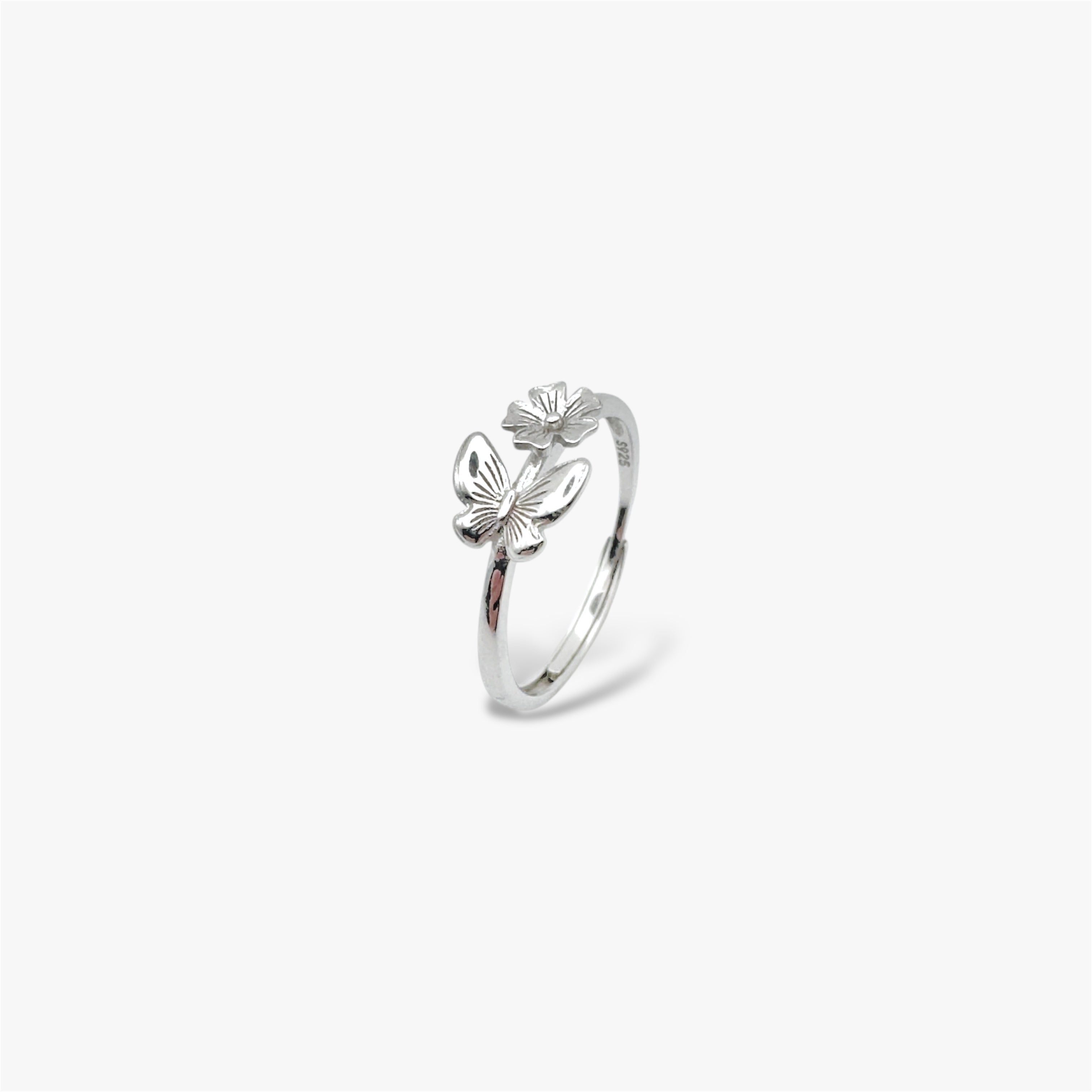 Angled view of silver ring with a floral design and a butterfly design.