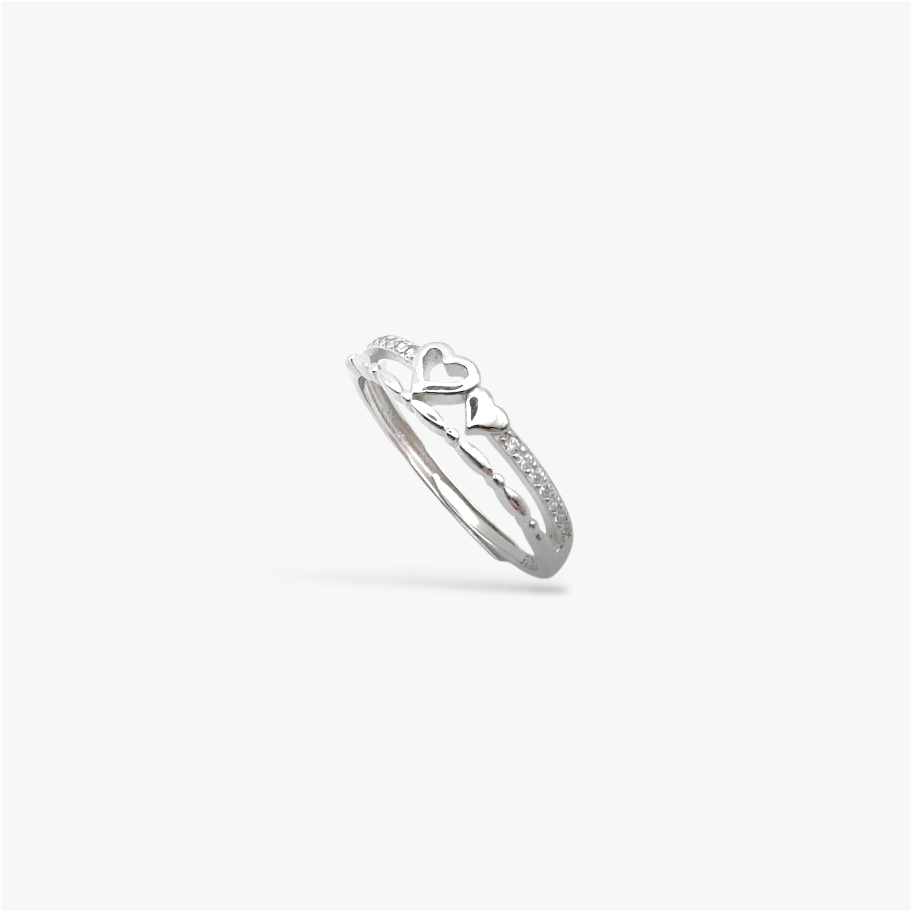Silver ring with a heart design and crystals at a sideways angle view.